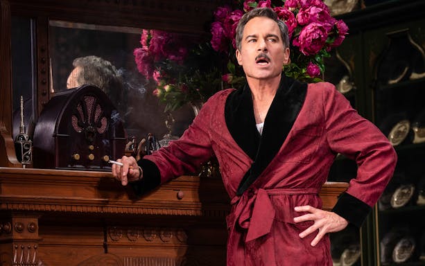 Man in a red robe with a vintage radio and flowers at The Cottage.