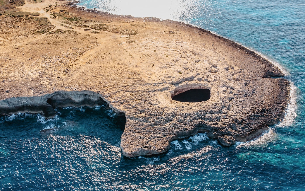 Aerial view of Ahrax fallen cave Coral Lagoon, Malta with surrounding coastline.