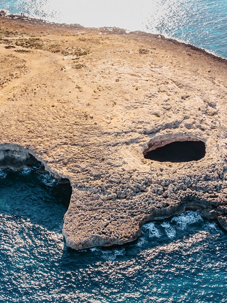 Aerial view of Ahrax fallen cave Coral Lagoon, Malta with surrounding coastline.