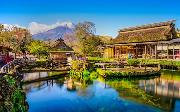 Oshino Hakkai village pond with traditional buildings and Mount Fuji in the background, Japan.