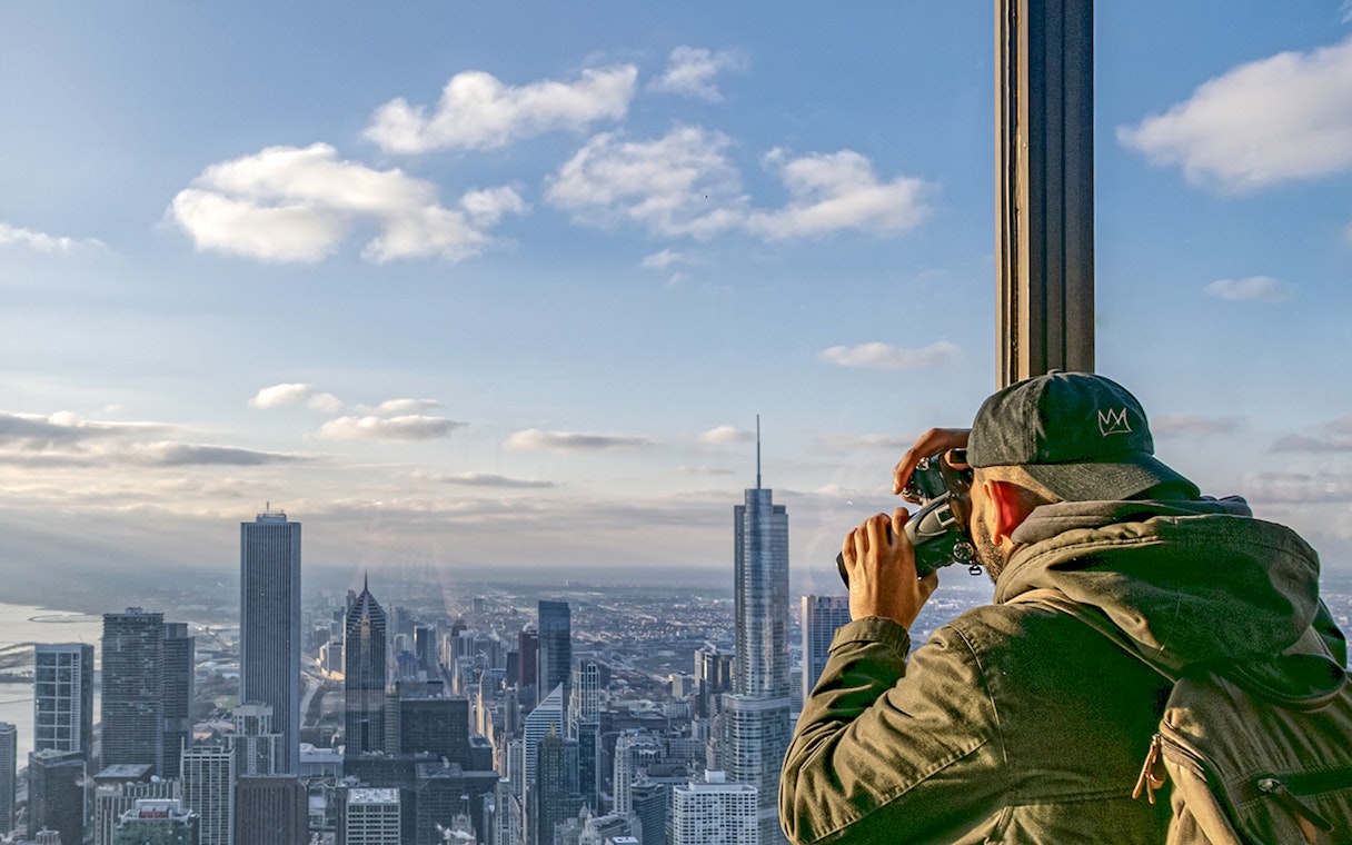 Guest photographing Chicago skyline from Skydeck during architecture tour.