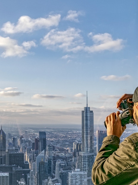 Guest photographing Chicago skyline from Skydeck during architecture tour.