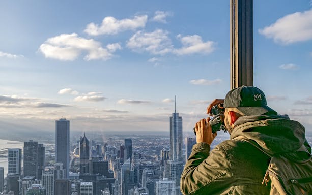 Guest photographing Chicago skyline from Skydeck during architecture tour.