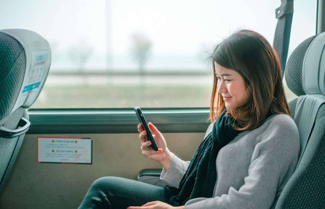 Woman using phone with Korea Unlimited Data eSIM in Seoul street.