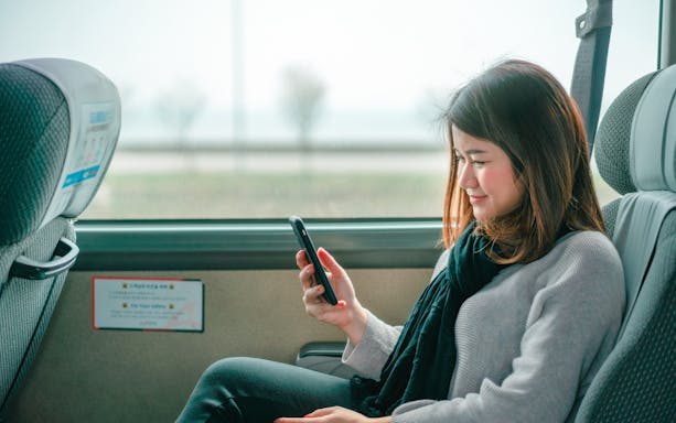 Woman using phone on a bus in Korea with unlimited data eSIM.