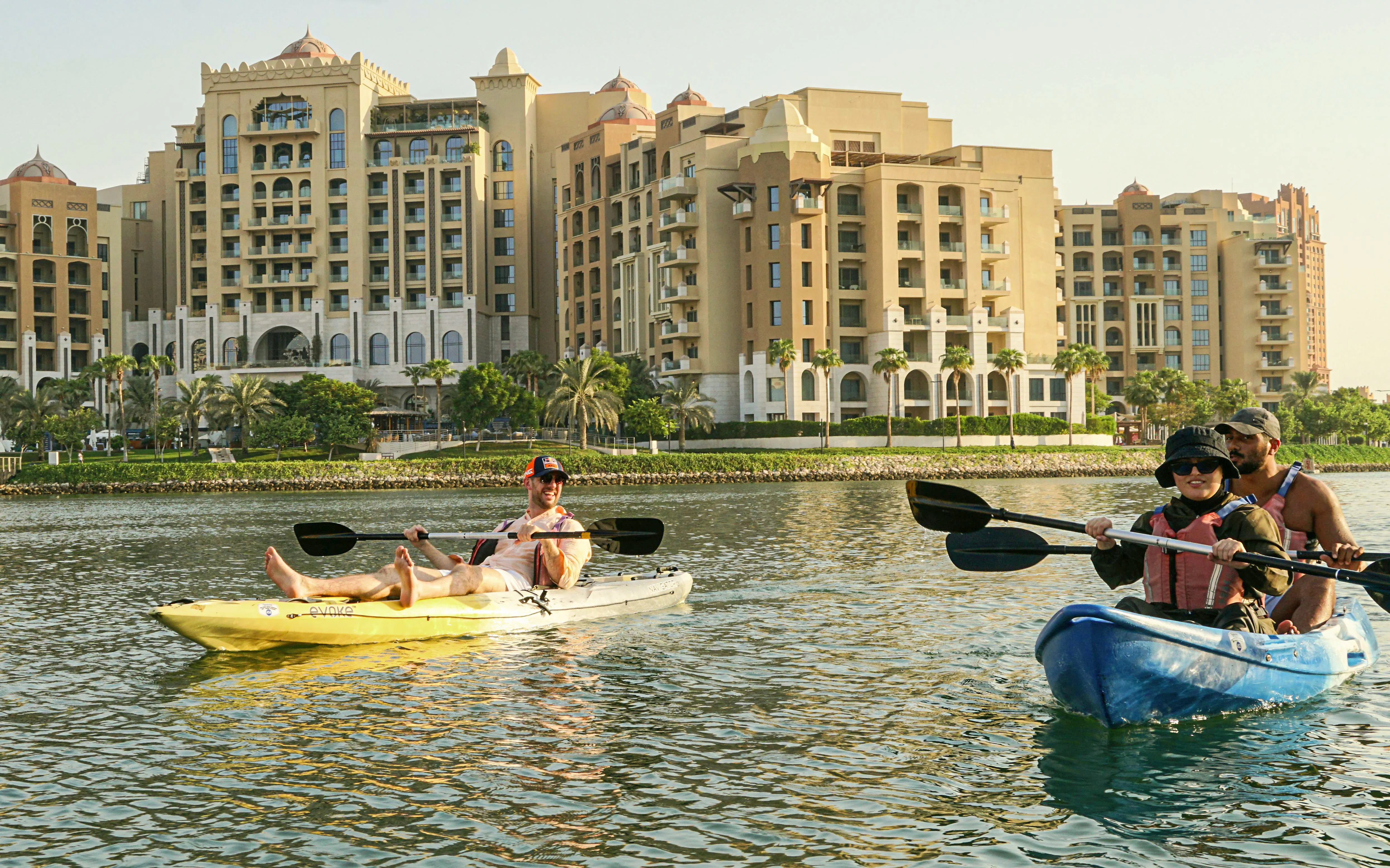 Kayakers paddling near waterfront buildings on The Pearl Guided Kayak Tour in Doha.