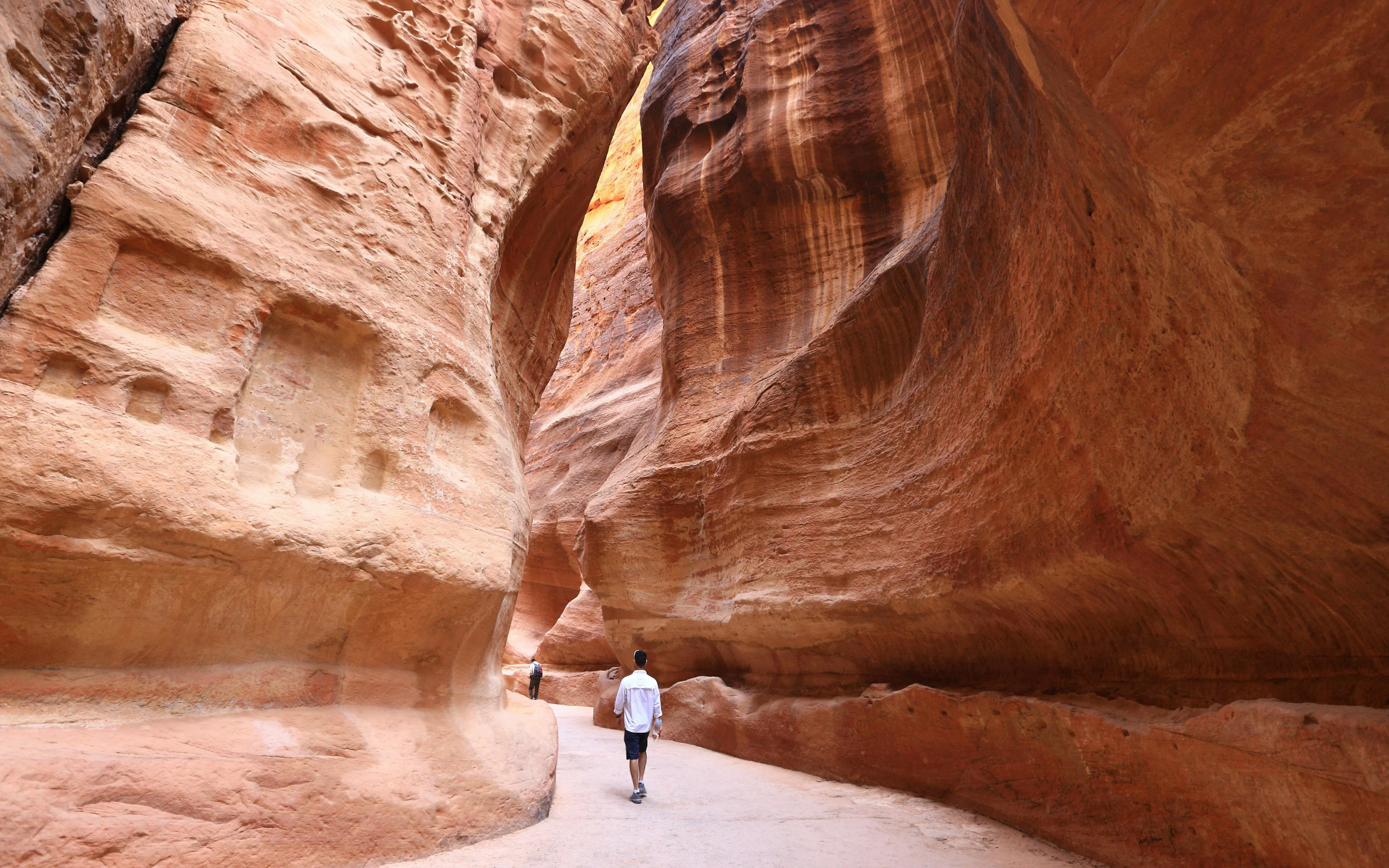 Visitors walking through the Siq, the narrow slot canyon entrance to Petra, Jordan.