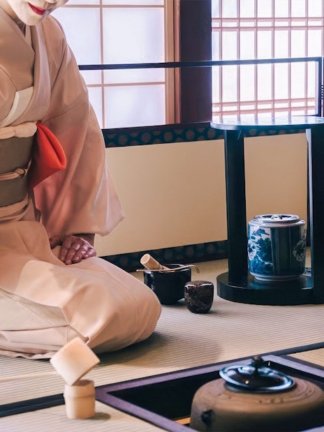 Traditional Japanese tea ceremony with kimono-clad host preparing matcha.