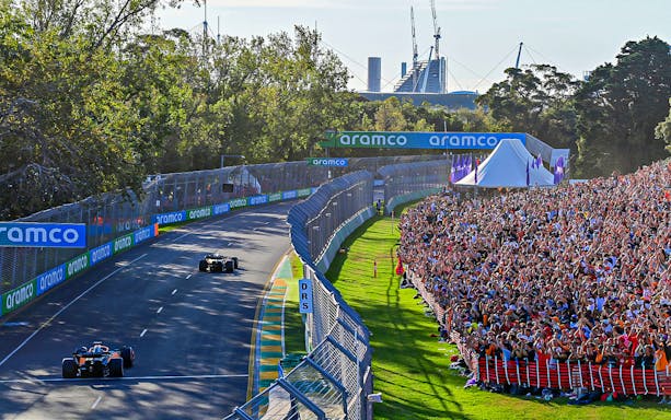 Formula 1 cars racing at the Australian Grand Prix 2023 with cheering crowd.