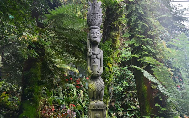 Stone statue surrounded by lush greenery at Gardens by the Bay, Singapore.