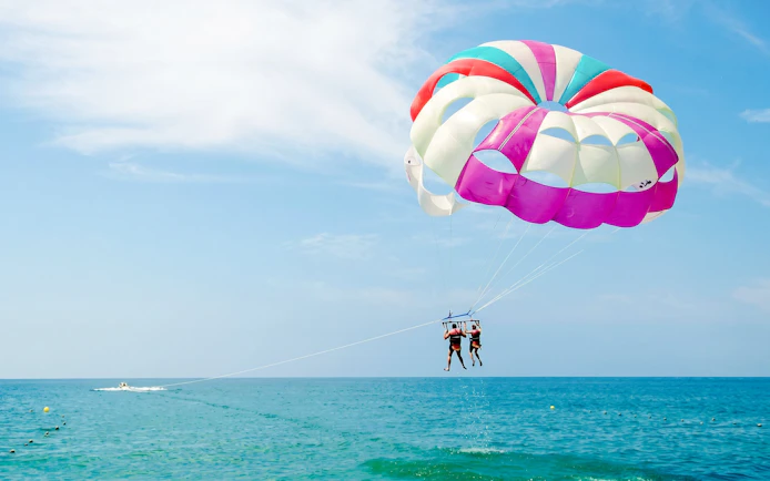 Parasailing over the ocean near Ile aux Cerf with colorful parachute.