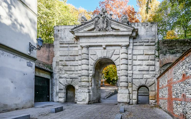 Gate of the Pomegranates entrance at Alhambra, Spain, with stone archway and surrounding trees.