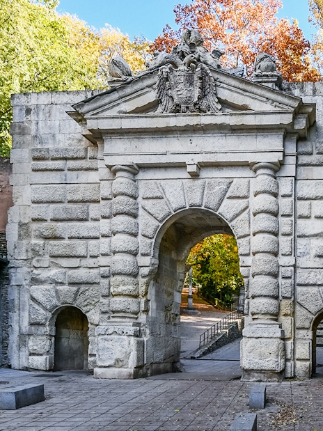 Gate of the Pomegranates entrance at Alhambra, Spain, with stone archway and surrounding trees.