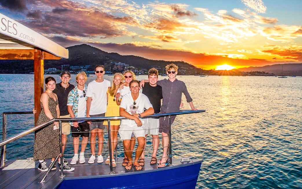 Tourists enjoying a sundowner cruise at sunset near Airlie Beach.
