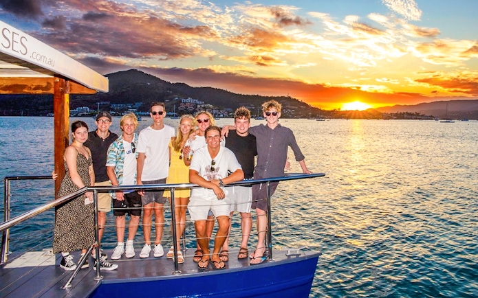 Tourists enjoying a sundowner cruise at sunset near Airlie Beach.