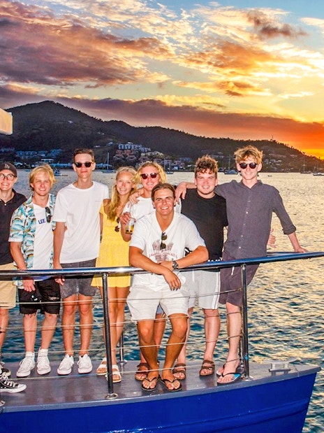Tourists enjoying a sundowner cruise at sunset near Airlie Beach.
