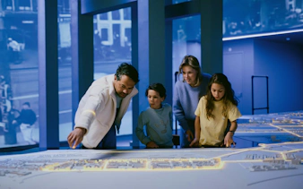 Family exploring interactive Amsterdam city model exhibit.