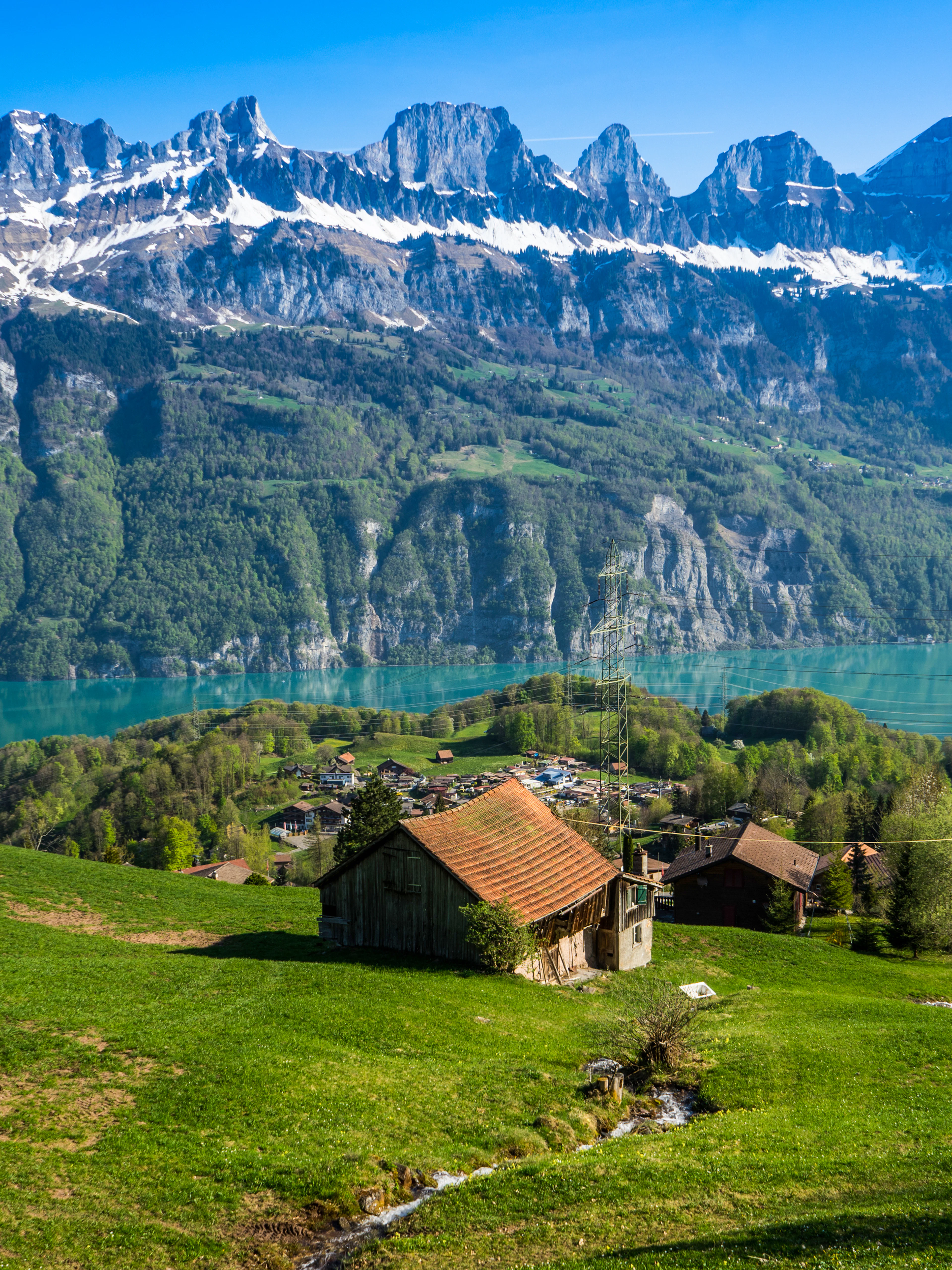 Swiss farmhouse overlooking Walensee lake with mountains in the background.