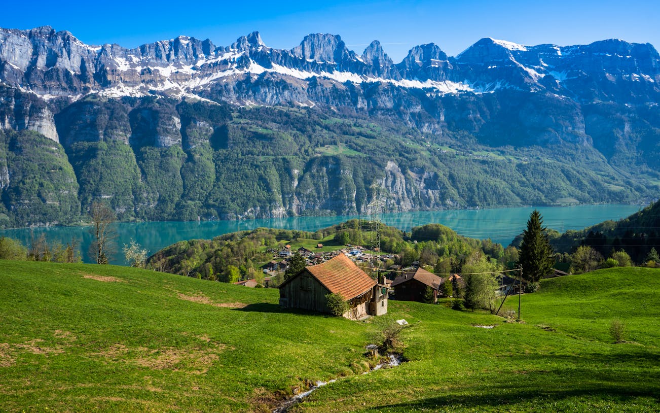 Swiss farmhouse overlooking Walensee lake with mountains in the background.
