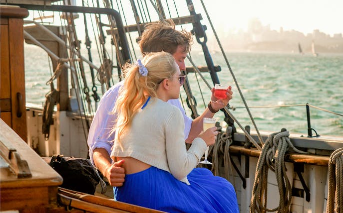 Couple enjoying drinks on a tall ship cruise on Sydney Harbour.