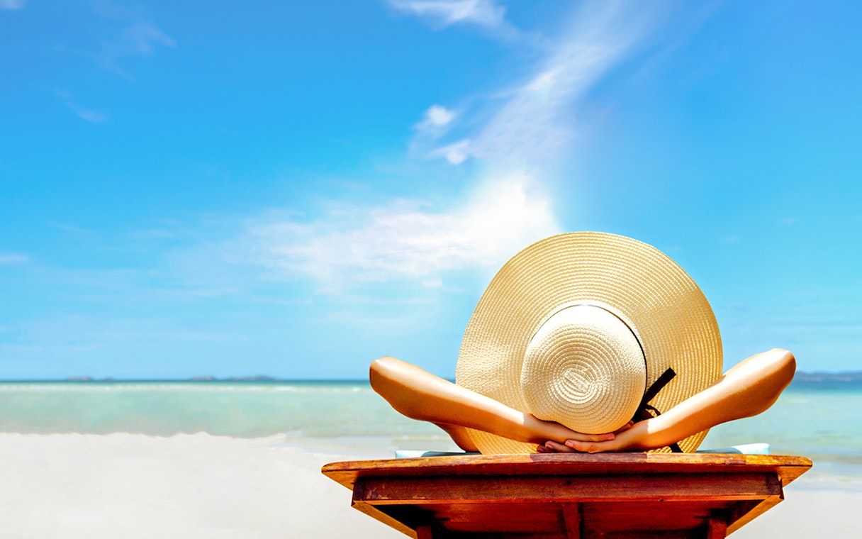 Person relaxing on a beach chair with a sun hat, overlooking the ocean in Bimini, Bahamas.