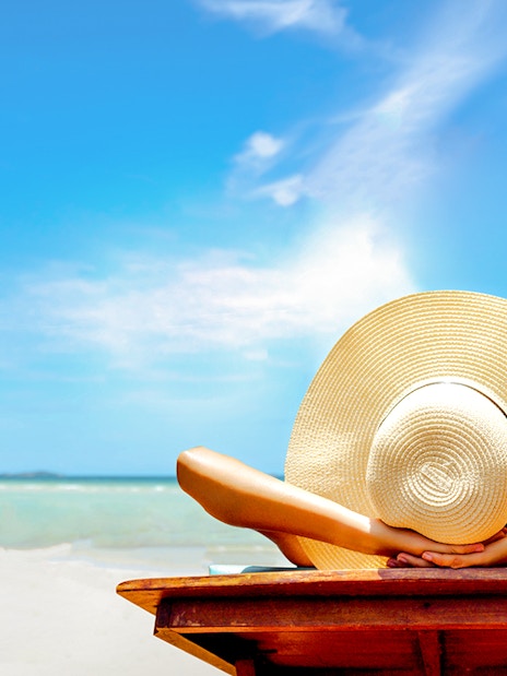 Person relaxing on a beach chair with a sun hat, overlooking the ocean in Bimini, Bahamas.
