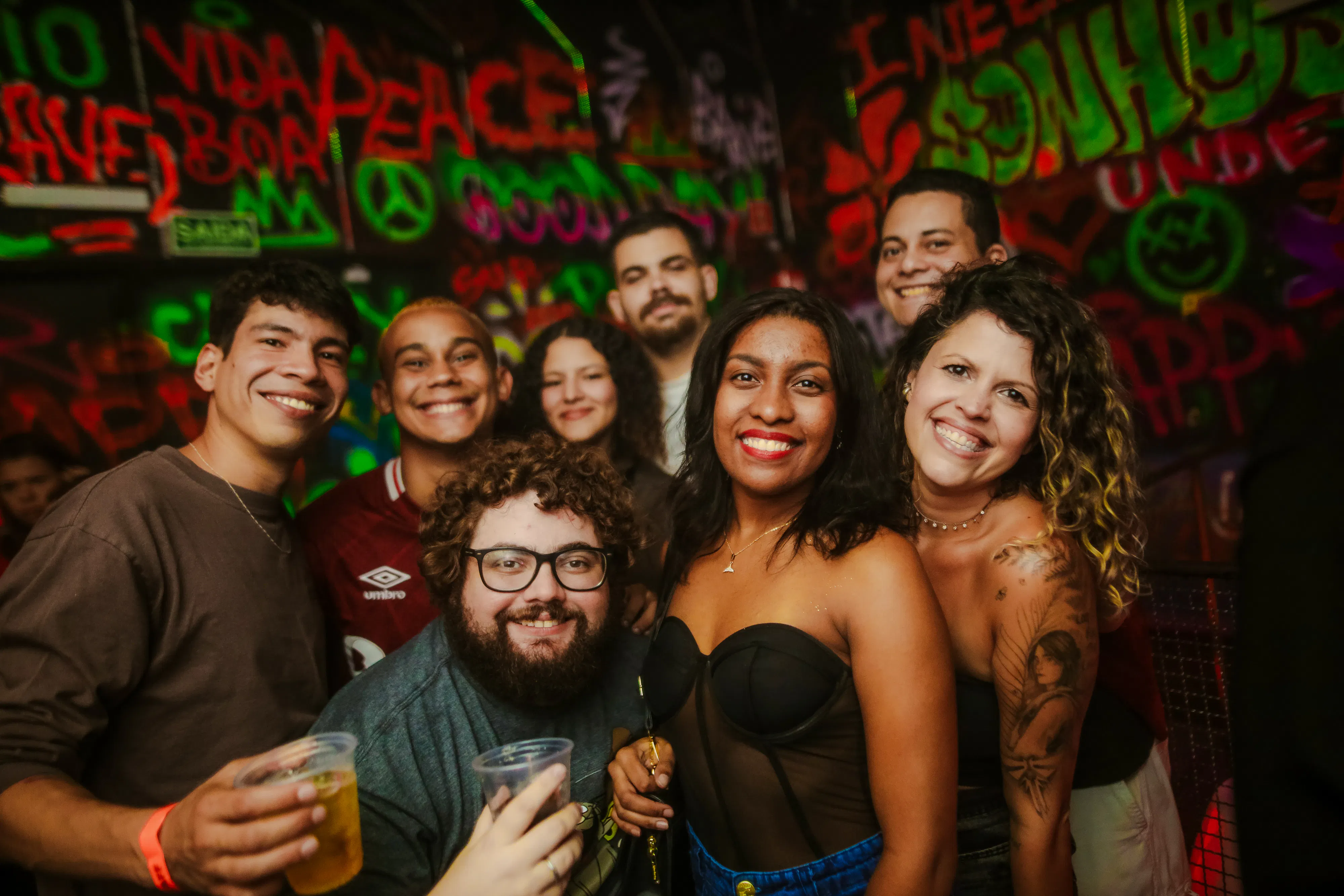Group enjoying nightlife at Substation Club Rio, Rio de Janeiro, with vibrant graffiti backdrop.