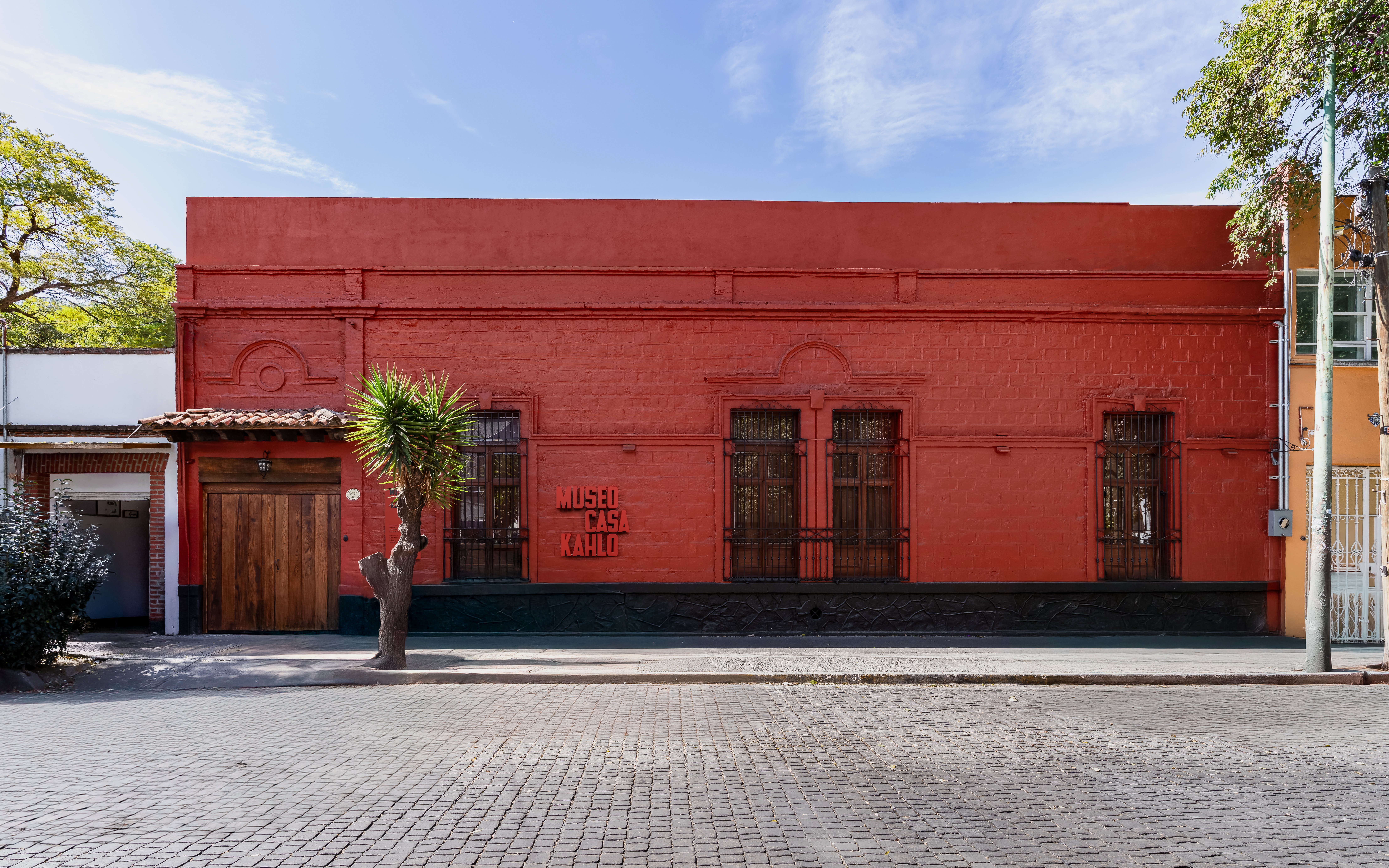 Museo Casa Kahlo exterior with red facade and wooden door in Mexico City.