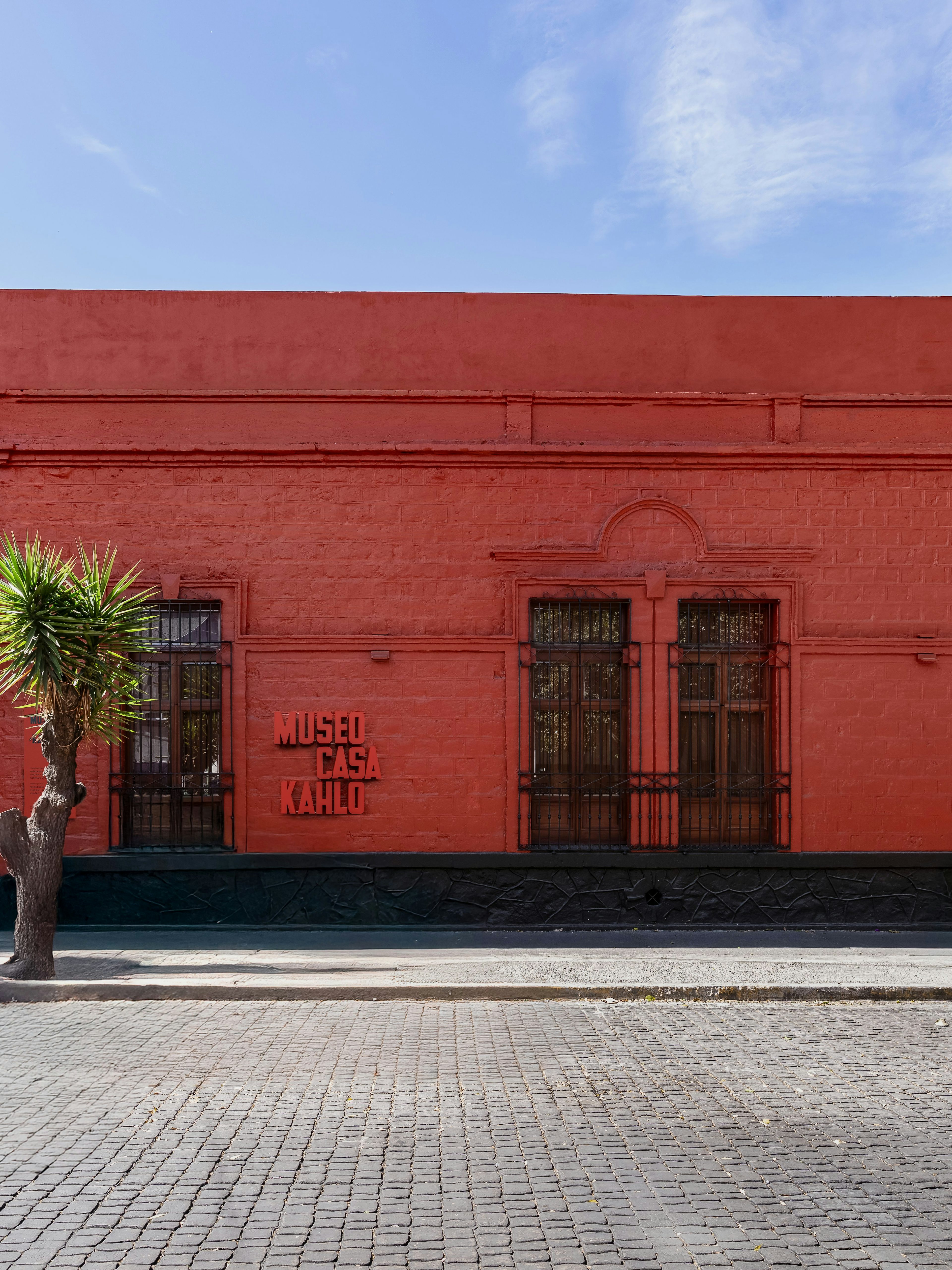 Museo Casa Kahlo exterior with red facade and wooden door in Mexico City.