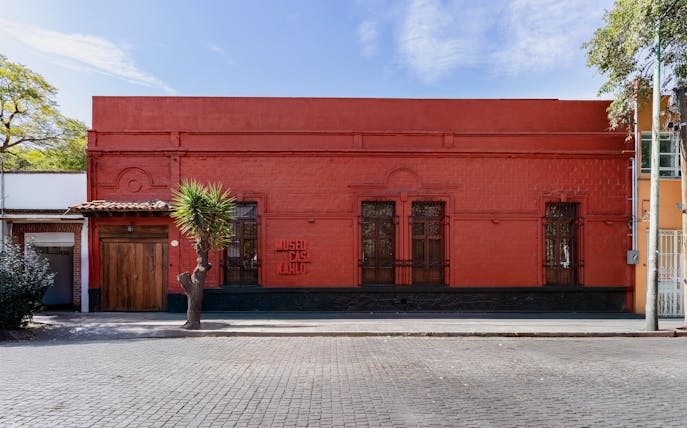 Museo Casa Kahlo exterior with red facade and wooden door in Mexico City.