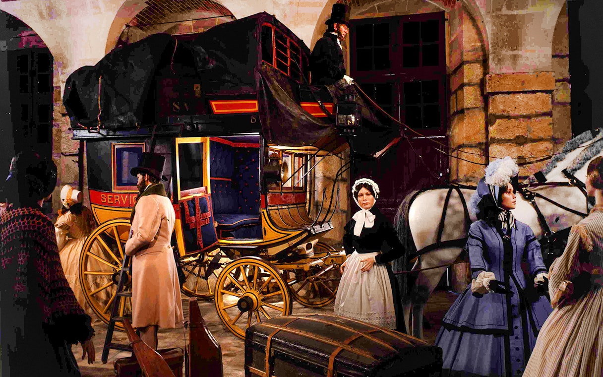 Carriage scene at Château of Vaux-le-Vicomte with period-dressed figures and horses.