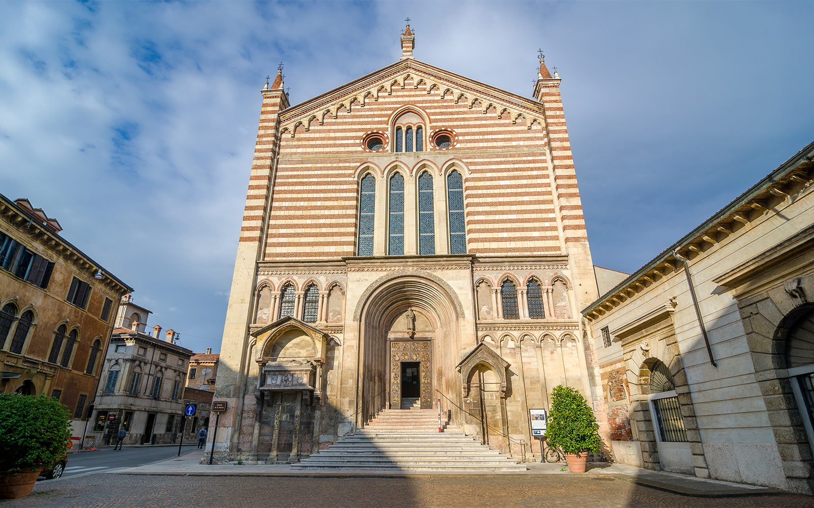 San Fermo Maggiore church facade in Verona, Italy, with striped brickwork and arched entrance.