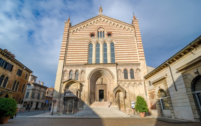 San Fermo Maggiore church facade in Verona, Italy, with striped brickwork and arched entrance.