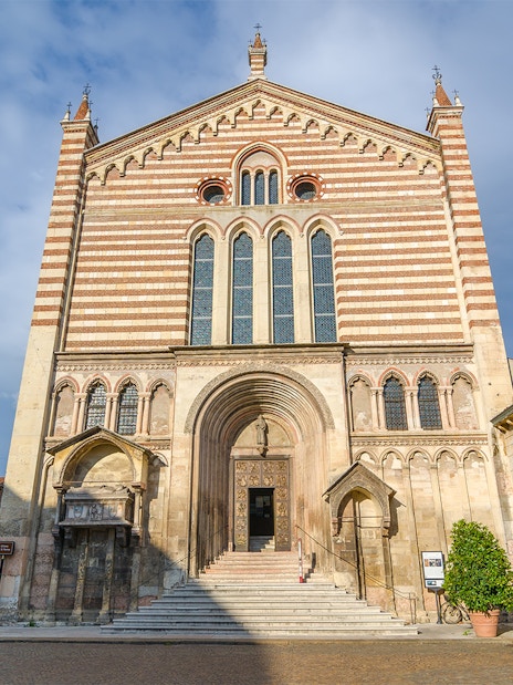 San Fermo Maggiore church facade in Verona, Italy, with striped brickwork and arched entrance.