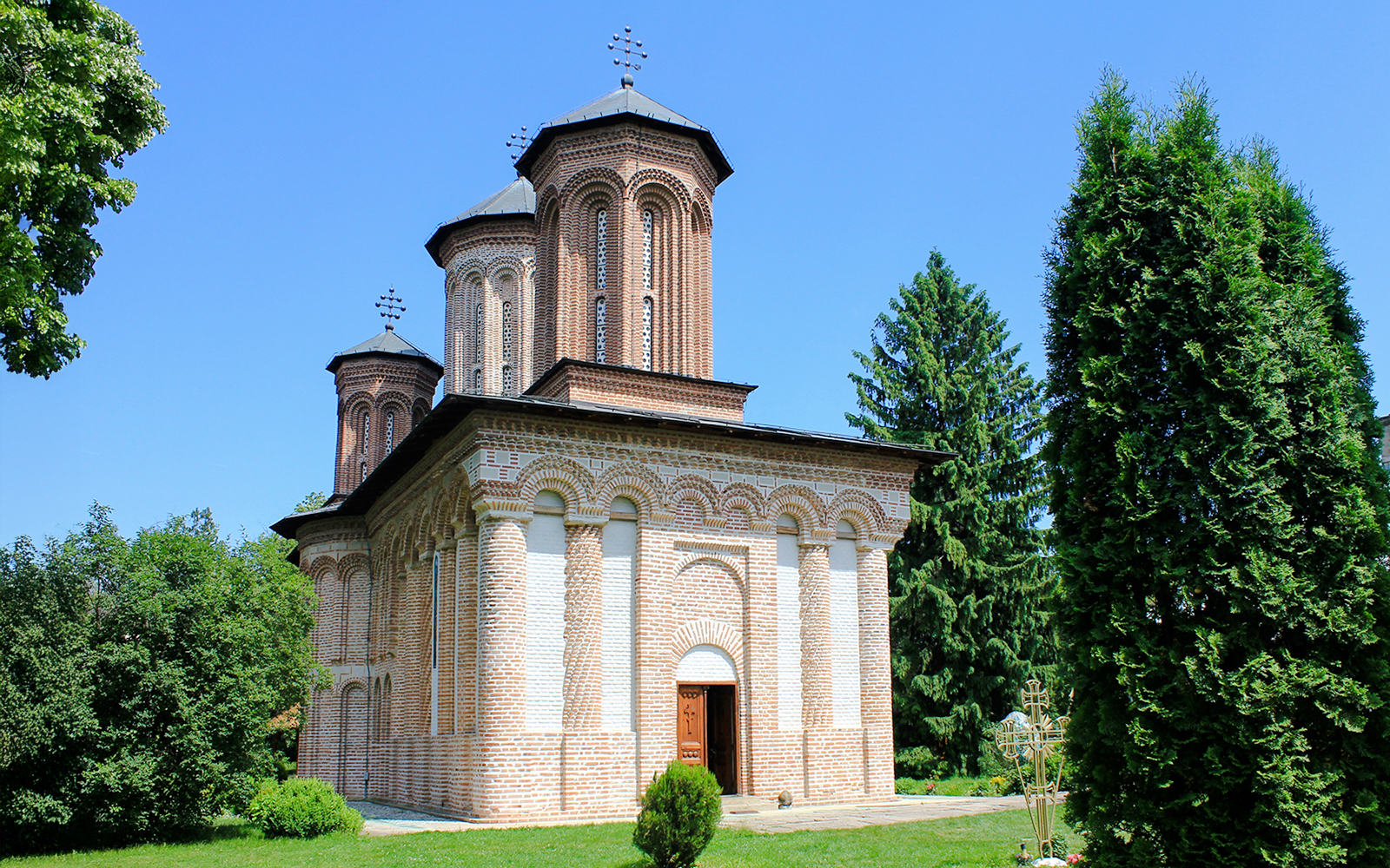 Exterior view of Snagov Monastery, Romania, featuring brick architecture and lush greenery.