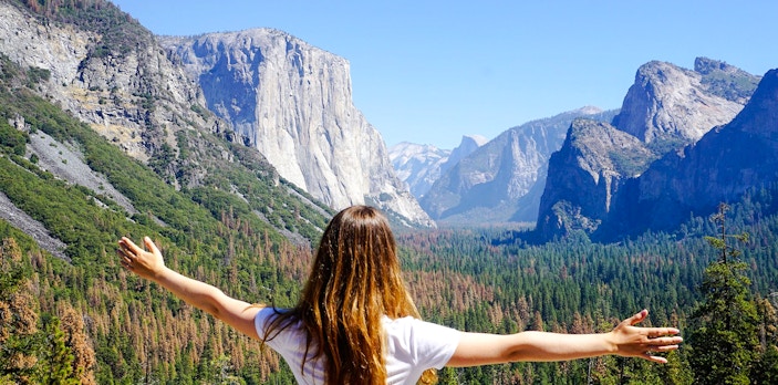 Person with arms outstretched overlooking El Capitan in Yosemite National Park.