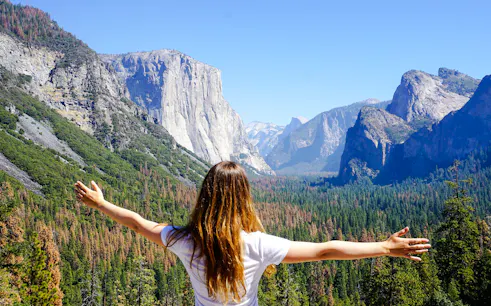 Person with arms outstretched overlooking El Capitan in Yosemite National Park.