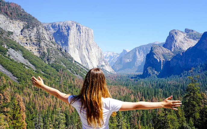 Person with arms outstretched overlooking El Capitan in Yosemite National Park.