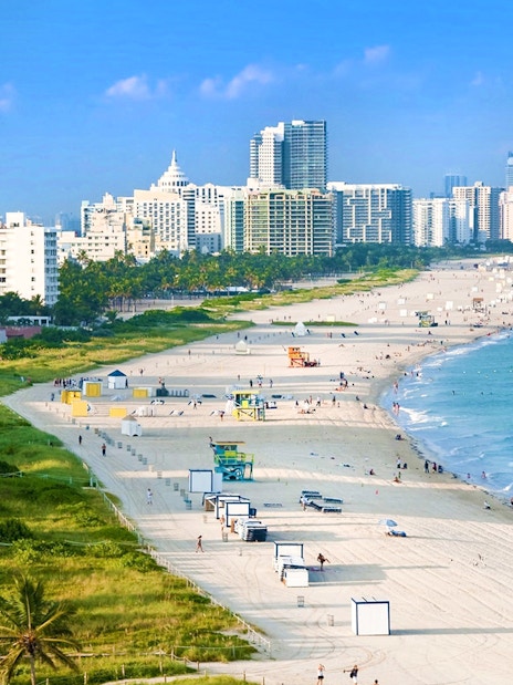 Miami beach coastline with high-rise buildings and lifeguard towers.