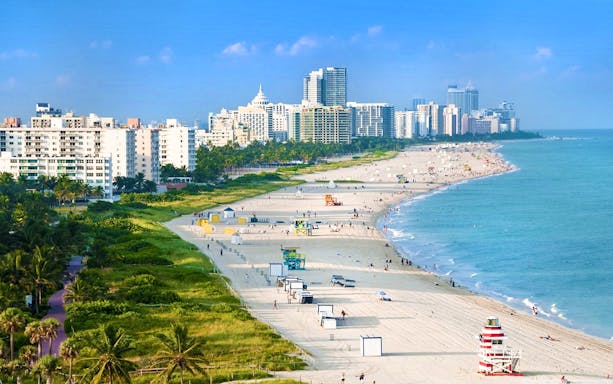 Miami beach coastline with high-rise buildings and lifeguard towers.