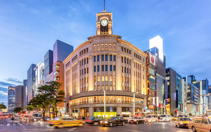 Wako Department Store in Ginza, Tokyo at dusk with busy street traffic.