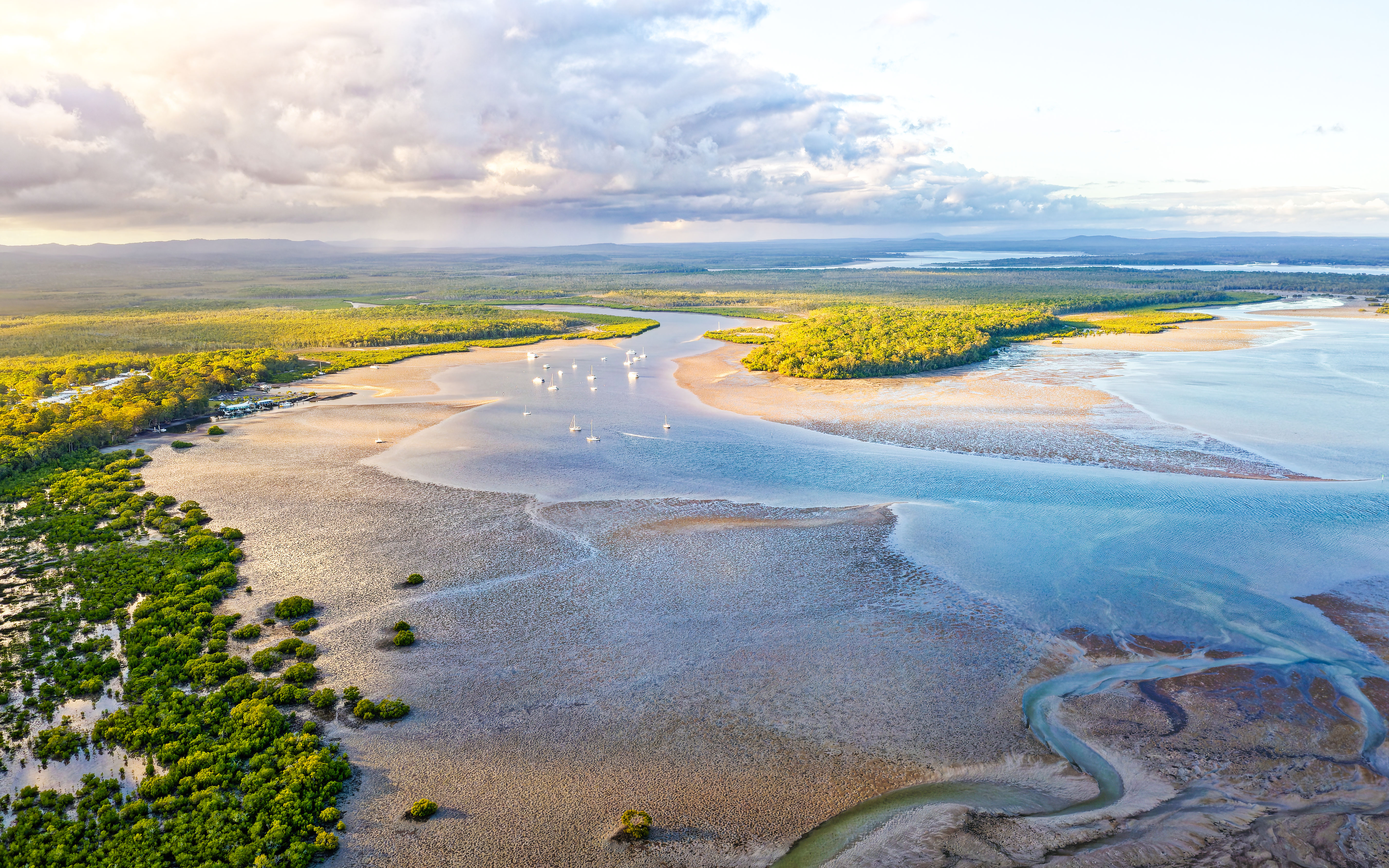 Aerial view of Great Sandy Strait with boats and lush green islands.