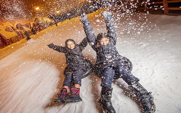 Children tubing down a snowy slope at Singapore Snow City.
