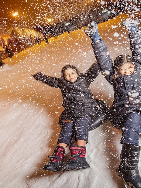 Children tubing down a snowy slope at Singapore Snow City.