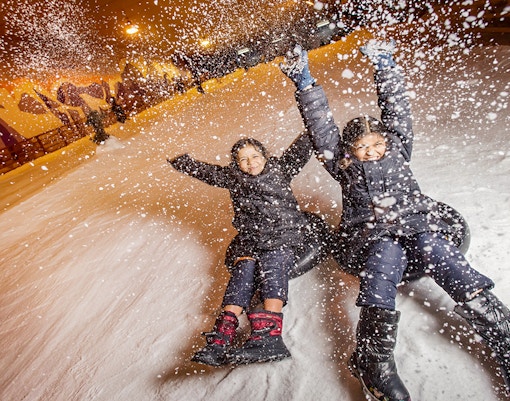 Children tubing down a snowy slope at Singapore Snow City.