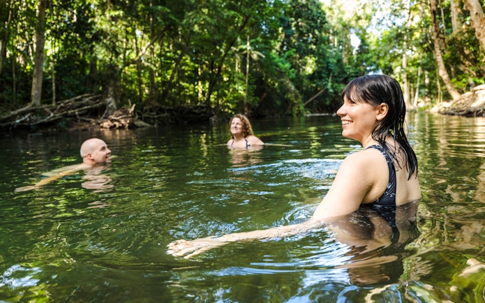 People swimming in a lush rainforest creek during Billy Tea Safaris tour, Daintree & Cape Tribulation.
