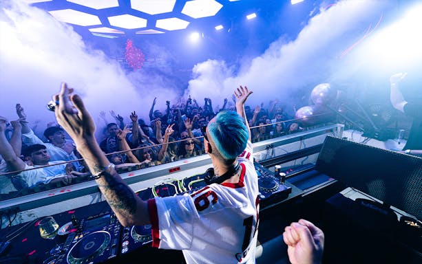 DJ performing at Pure Pacha Ibiza with crowd dancing and lights.