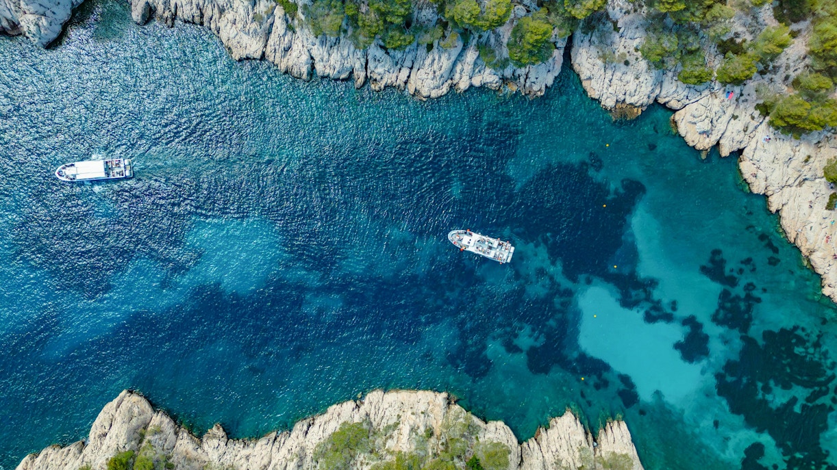 Excursion boats navigating the turquoise waters of Calanques de Cassis, France.