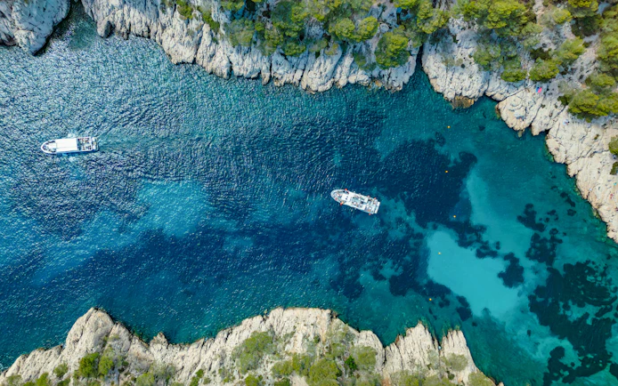 Excursion boats navigating the turquoise waters of Calanques de Cassis, France.