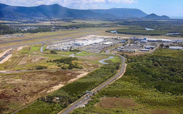 Aerial view of Cairns Airport with surrounding landscape and roads.
